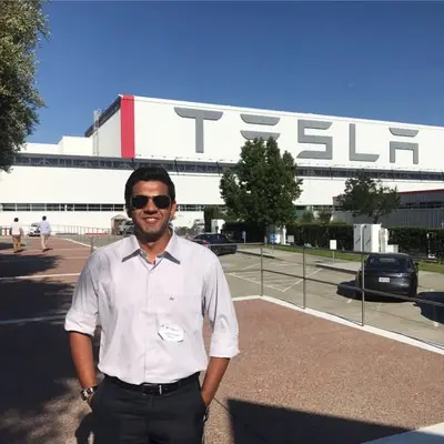 سیدهنت آواستھی، سرپرست برنامه سایبرترک تسلا، در مقابل یک ساختمان تسلا ایستاده است.