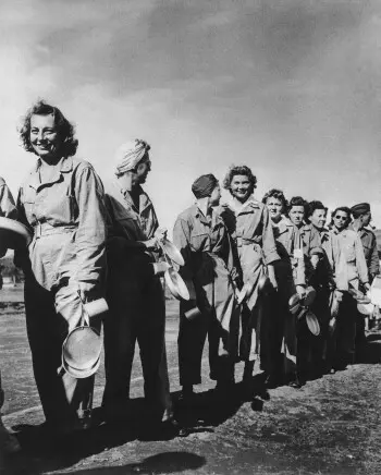 پرستاران ارتش ایالات متحده در بیمارستان‌های تخلیه در ایتالیا تحت شرایطی مشابه به آنچه سربازان تجربه می‌کردند، مشغول به کارند؛ این دختران که شغلی سخت و زندگی دشواری دارند، هنوز توانستند جنبه‌های مثبت را ببینند؛ در این عکس، پرستاران با لبخند در صف غذا در یک بیمارستان تخلیه در جایی از ایتالیا، ۶ فوریه ۱۹۴۴، ایستاده‌اند. آن‌ها لباس‌های یک‌پارچه‌ای مطابق با مقررات برای چنین مأموریتی می‌پوشند (عکس AP)