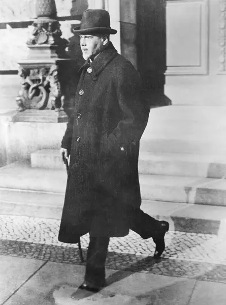 عکس سیاهوسفید مردی با سبی، کت بلند و کلاه، والتر راثنائو در سال ۱۹۲۲ که در حال پایین رفتن از پلهها است.