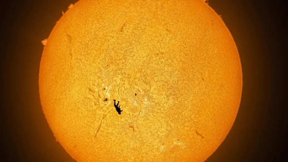 عکس خورشید با سیلوئت یک پاراشوتگیر در جلو