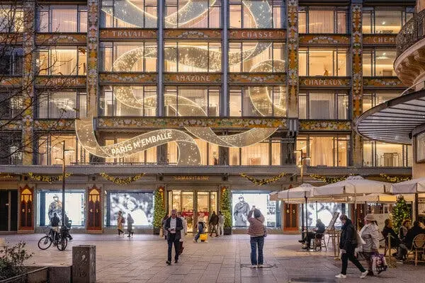 نمای بیرونی ساختمان ساماریطان، تزئین‌شده برای کریسمس ۲۰۲۵. یک روبان طلای عظیم به‌نظر می‌رسد که از میان پنجره‌های متعدد پیچیده و حاوی عبارت «PARIS M’EMBALLE» است