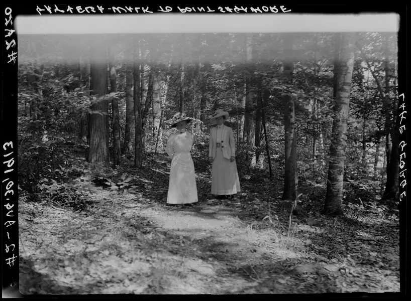 دو زن دوره ویکتوریایی در یک منطقه جنگلی ایستاده‌اند.