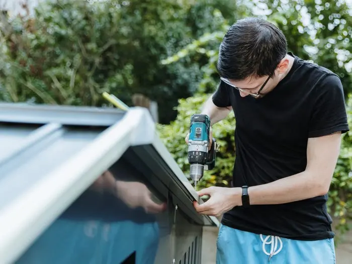 مردی که در حال سوراخکاری سقف یک انباری ابزار است