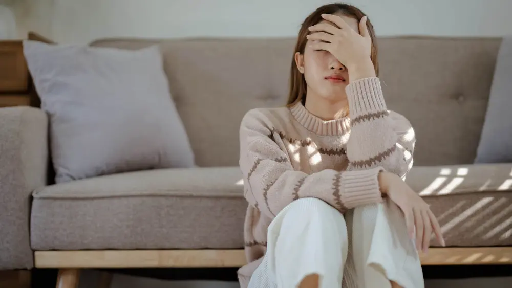 زن اضطراب‌زده‌ای که احساس جدایی از لذت‌های کوچک دارد و تنها نشسته