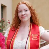 شارلوت فیلپ لباسی سفید و روبان قرمز به تن دارد که نوشته‌های «Magna Cum Laude» و «USC Annenberg» را به نمایش می‌گذارد