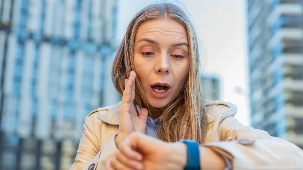 زن با حس اضطراری به ساعت نگاه میکند