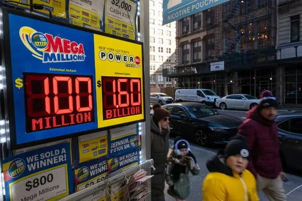 افراد در حال عبور از فروشگاهی هستند که در پنجرهاش تابلوهای نمایش جکپات لاتاری نصب شدهاند.